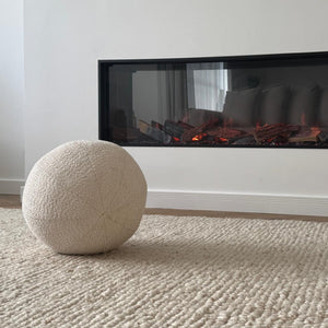 White textured ball on a beige carpet in front of a modern fireplace.