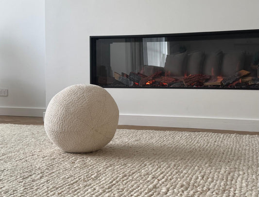 White textured ball on a beige carpet in front of a modern fireplace.